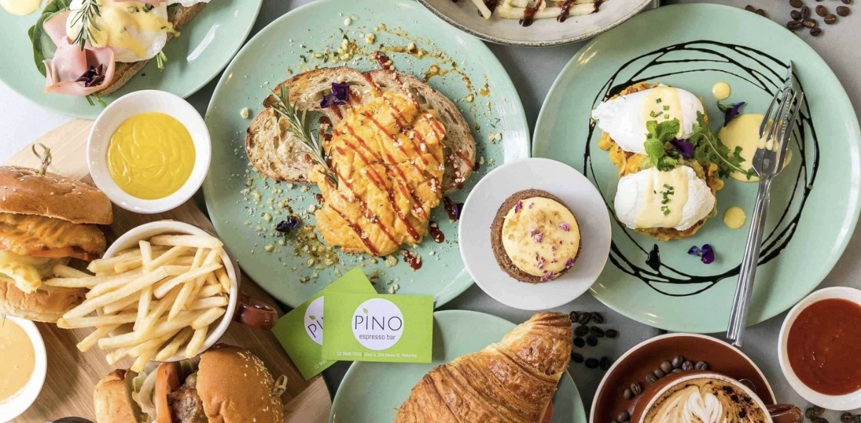 A spread of Pino Espresso Bar breakfast dishes, burgers, croissants and coffee